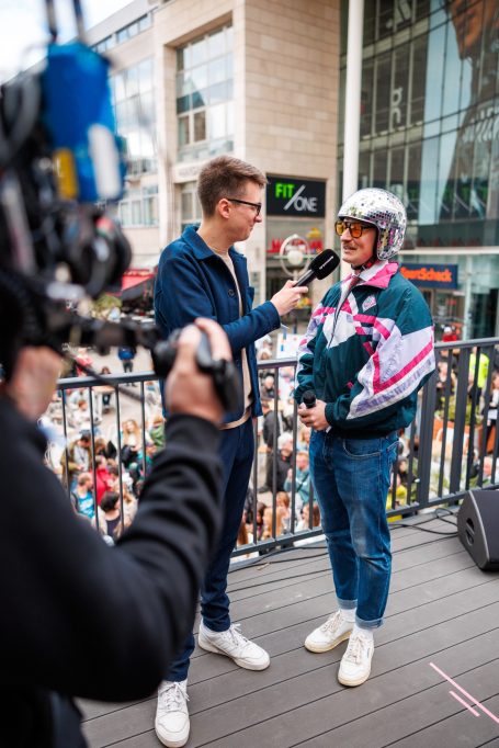 Ein Interview mit einer Person in Sportkleidung vor einer Menschenmenge.