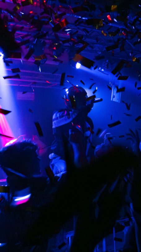 Bunte Lichter und Konfetti bei einer Live-Musikveranstaltung in einer dunklen Umgebung.